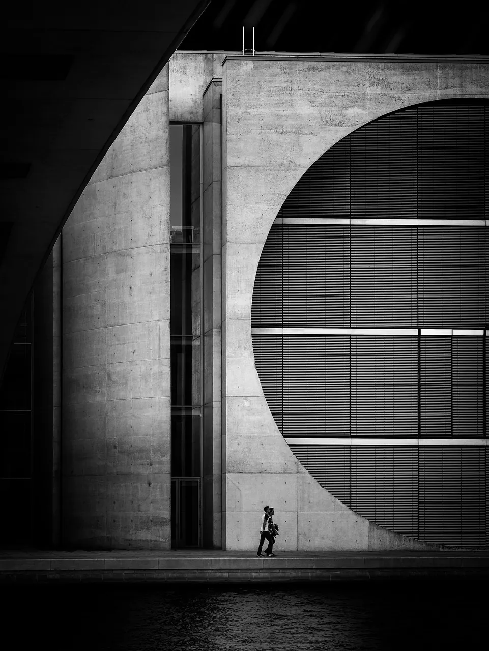 A dark concrete monolith with a circular void, photographed in black and white