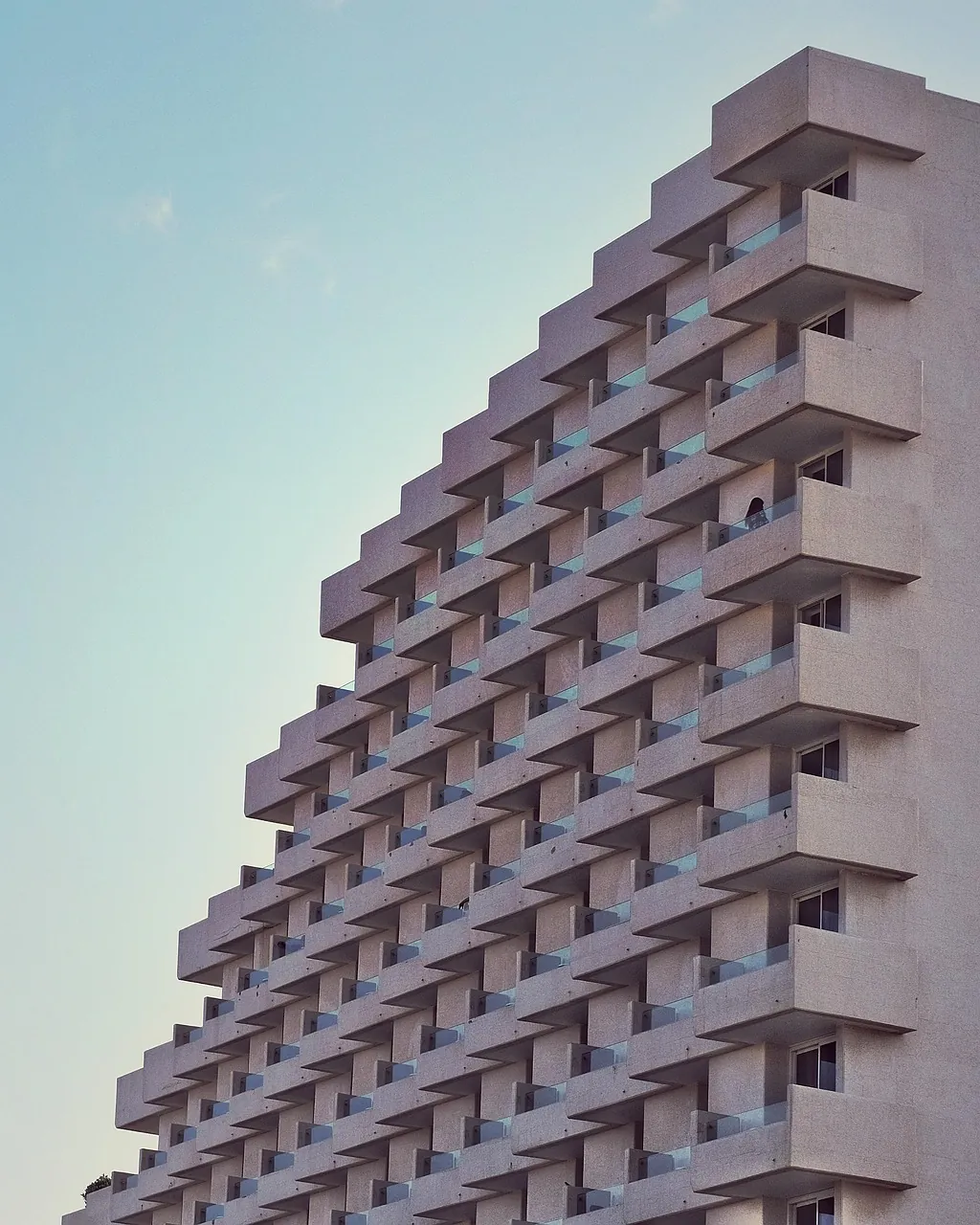 Stepped white balconies of a housing block against open sky